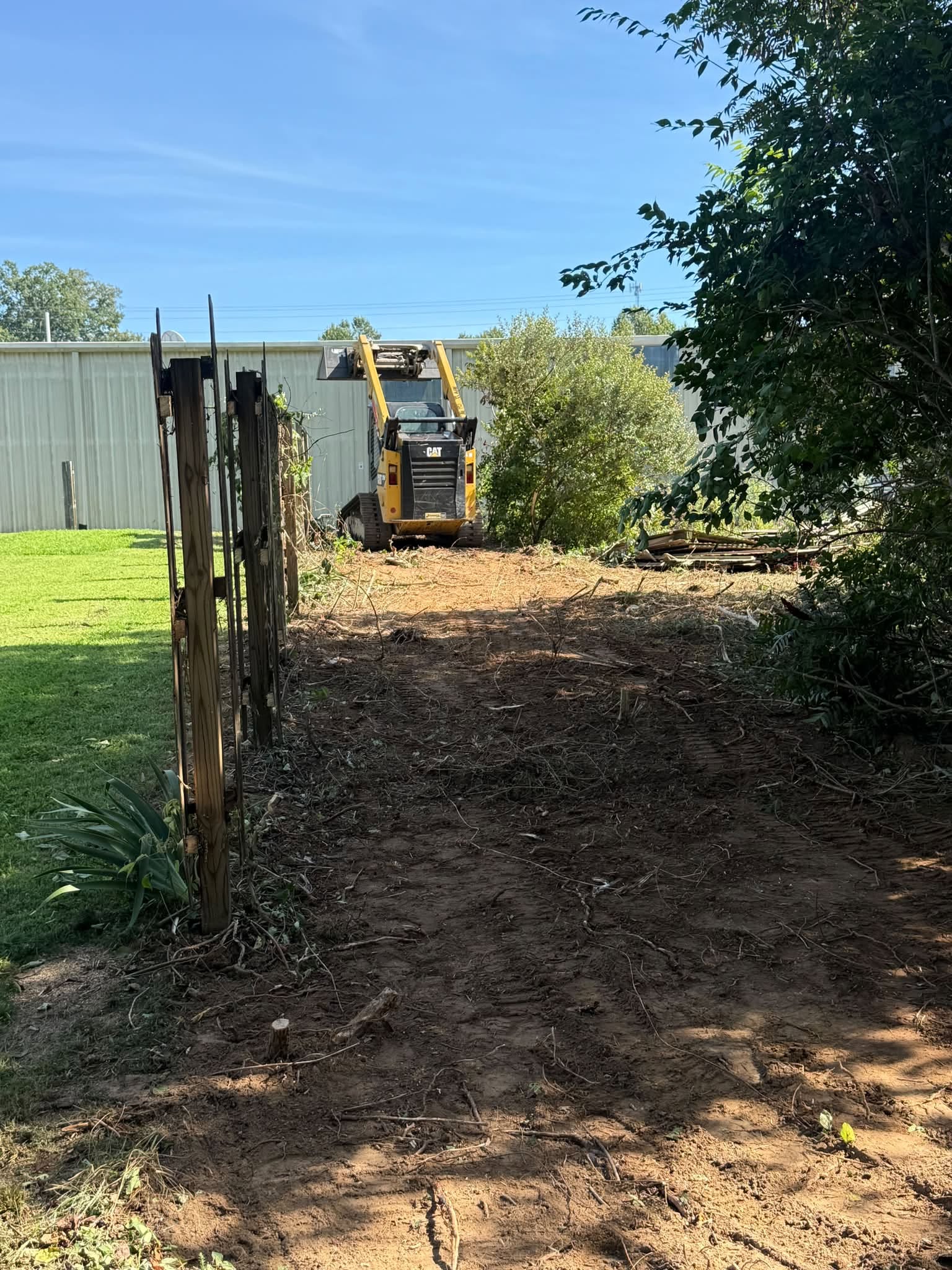 Tennessee Fence Systems crew at work on a fence job site with a skid-steer